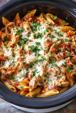 Family slow cooker chicken parmesan pasta served in a large bowl topped with melted cheese and basil